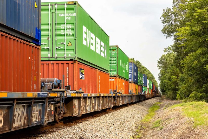 Freight train carrying intermodal shipping containers through a rail yard